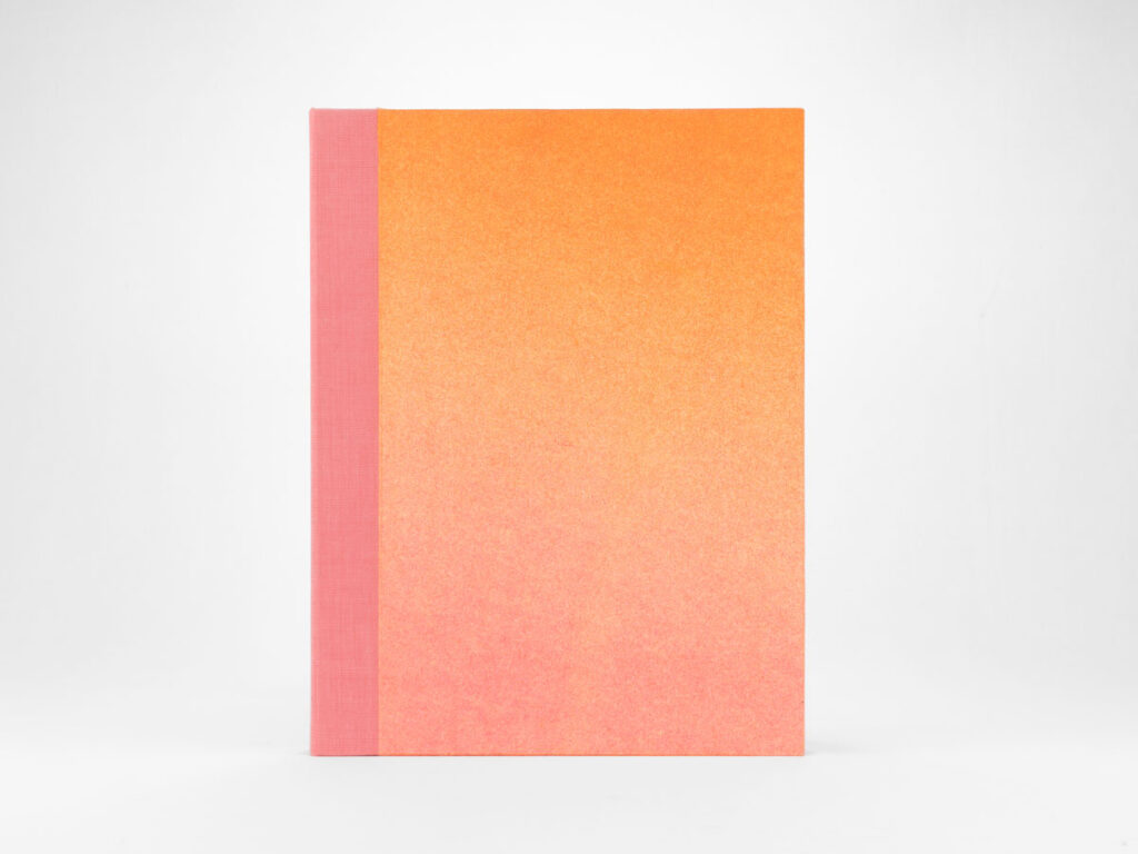 foto de caja para el fotolibro accidentes geográficos formato vertical degradé naranja rosado y lomo en tela rosada